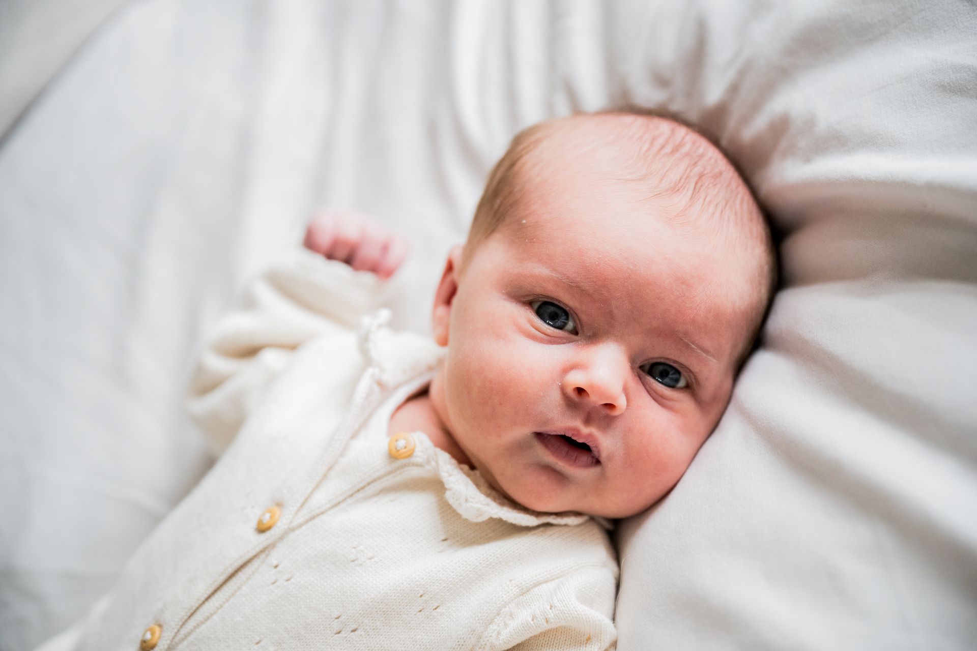 Pasgeboren baby wakker in wieg – lifestyle newborn fotoshoot aan huis in Boxtel