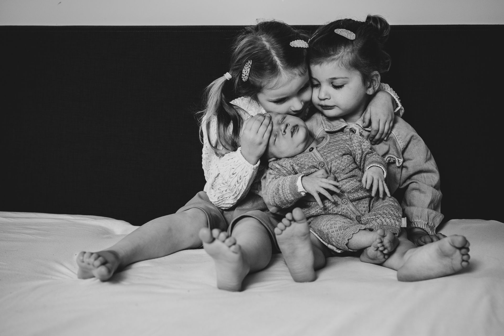 Zwart-wit newborn foto – twee zusjes knuffelen samen, lifestyle gezinsfotografie door Charlène in Boxtel